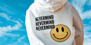White sweatshirt with smiley face with blue sky and white clouds in the background